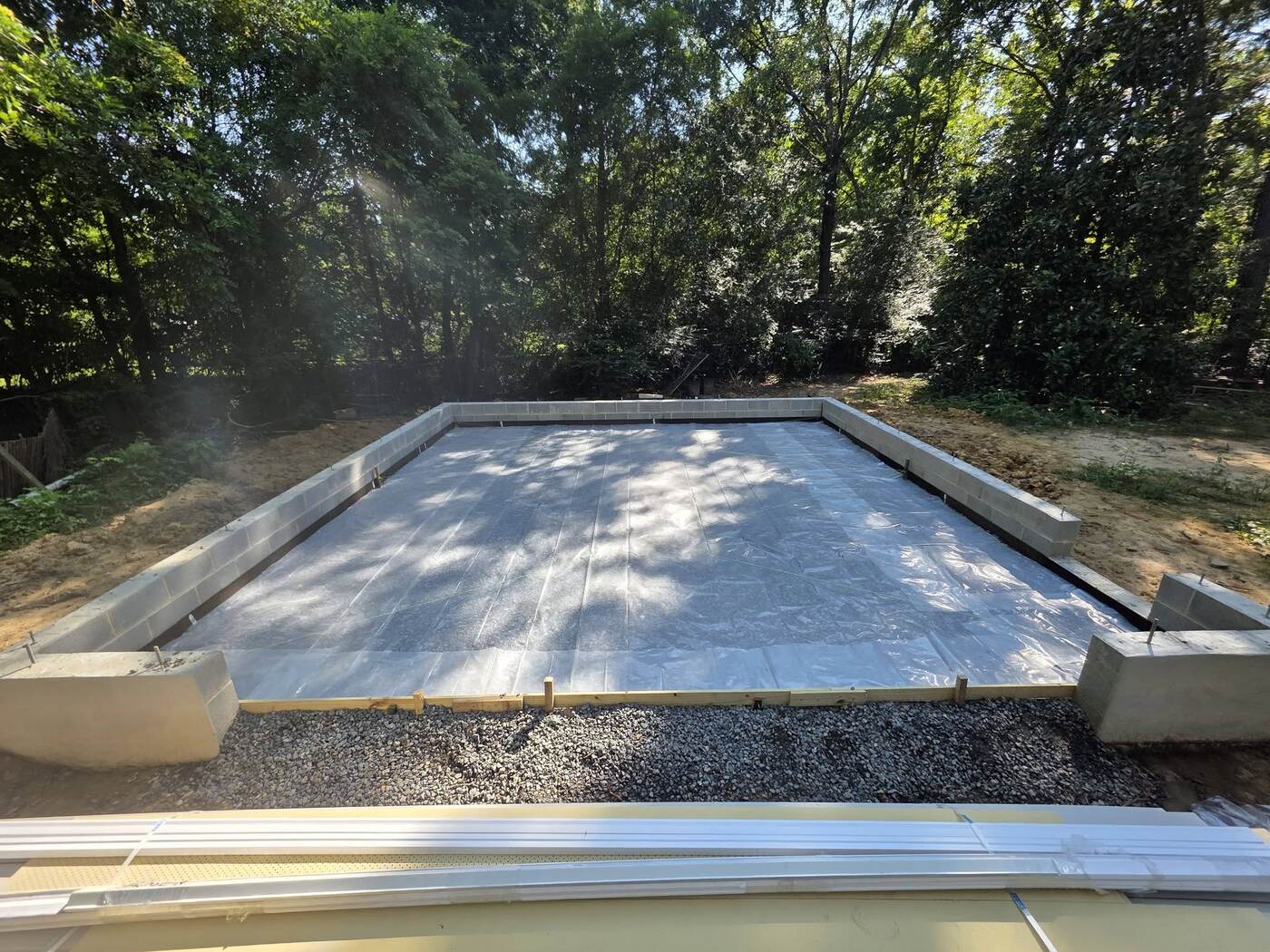 After: Laser graded, compacted gravel base and vapor barrier ready for concrete floor